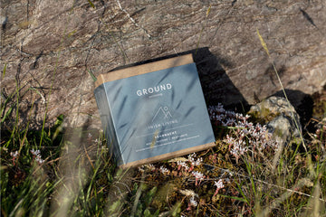 Ground Wellbeing & Inish Living Beannacht box with sleep aiding oil sitting in grass with a rock behind it