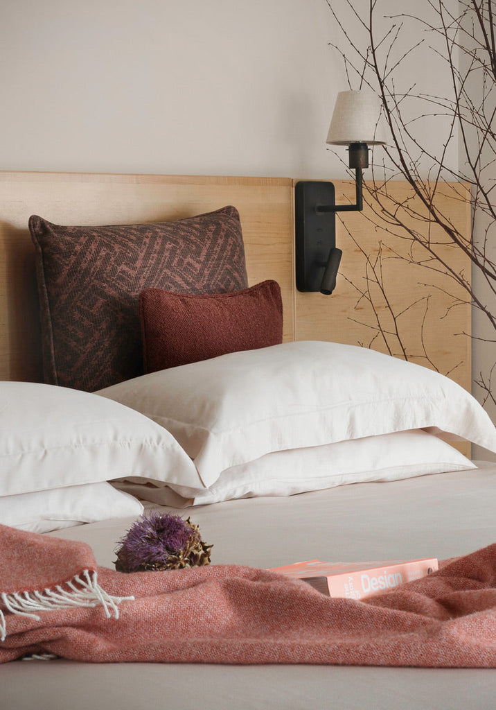 Luxury bed linen from Inish Living, based in southwest Ireland. Set up on a made bed with a blanket draped over it.