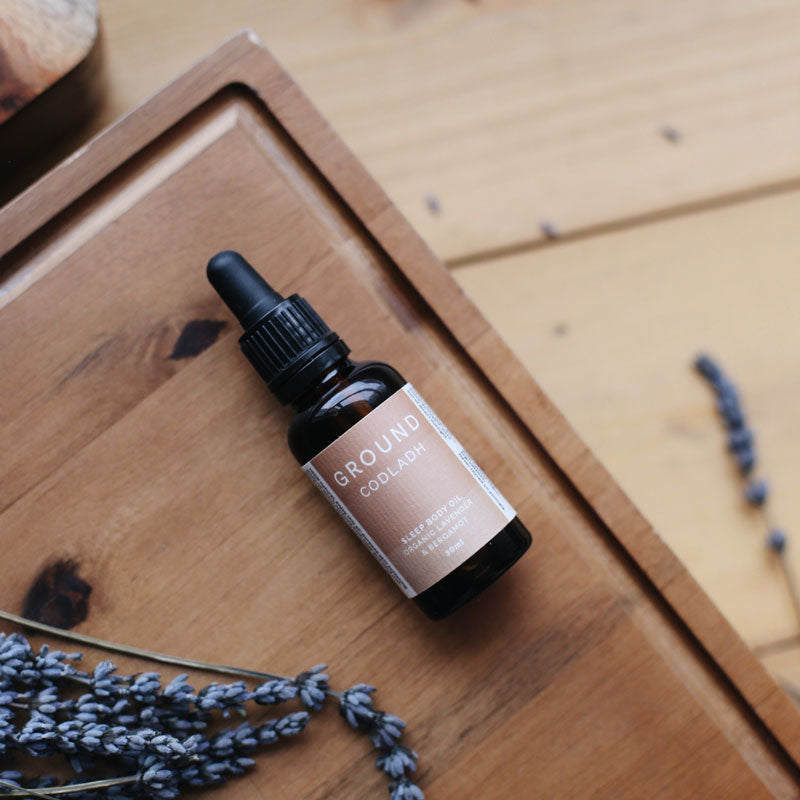 Bottle of oil called Ground Codladh Sleep body oil on a wooden table
