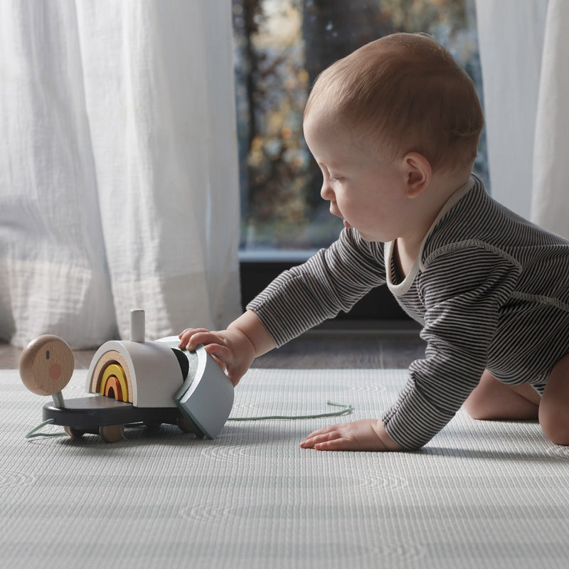 Young baby playing with a toy on the Inish Living Playmat